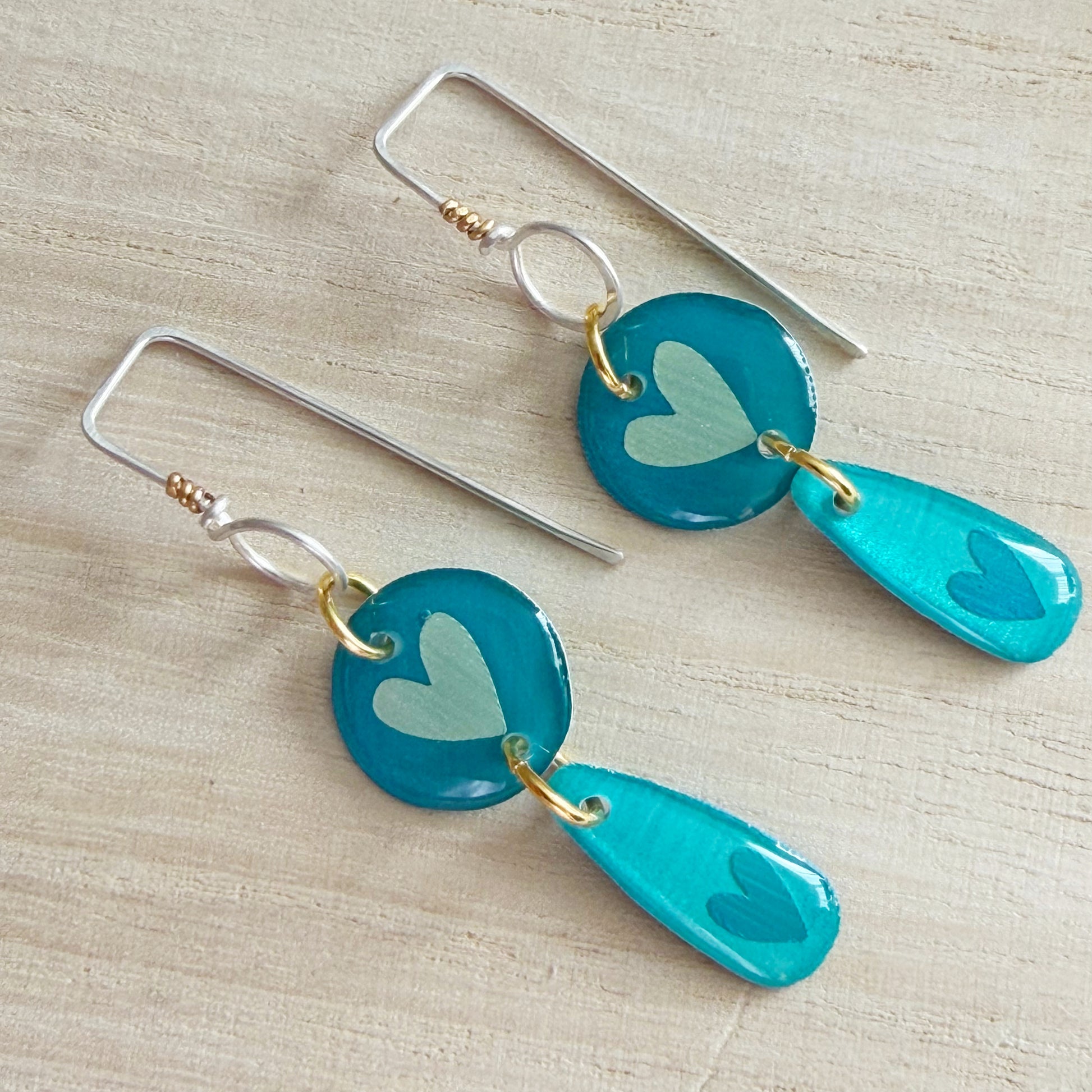 aqua heart-shaped earrings on a wooden surface