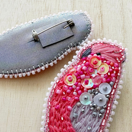 Decorative brooch with pink and gray design on a light wooden surface