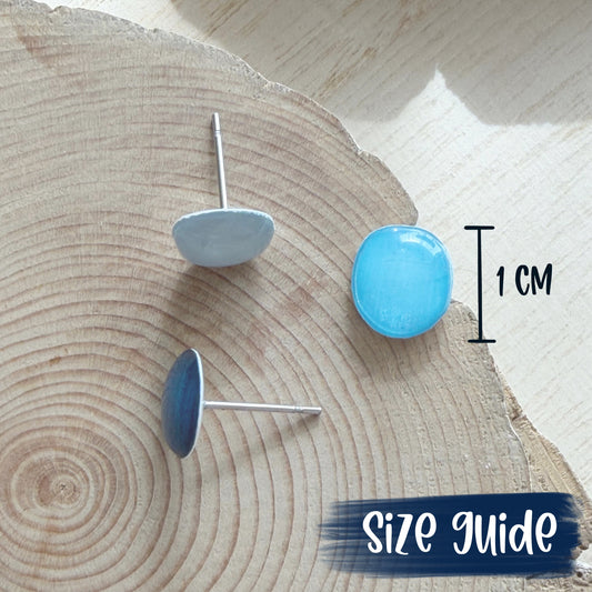 Blue round earrings on a wooden surface with a size guide indicating 1 cm.